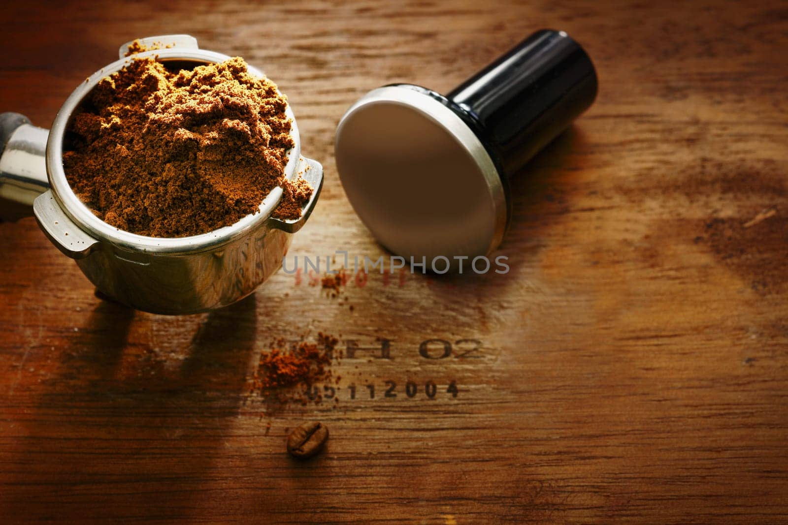 Freshly ground coffee beans in a metal filter on a wooden background with copyspace during preparation of a cup of aromatic filter coffee or espresso