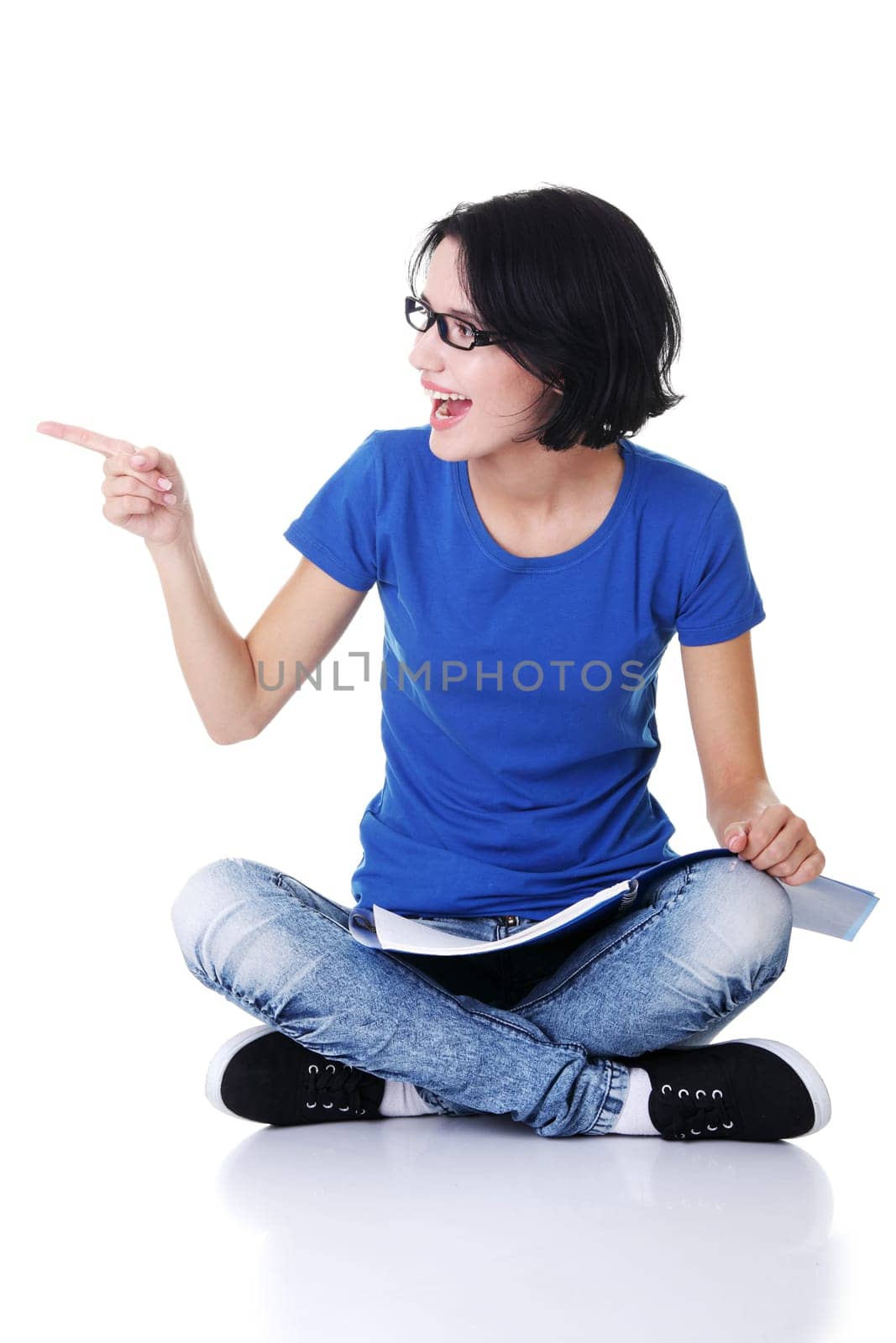 Studying happy young woman reading her notebook for school and pointing on copy space.