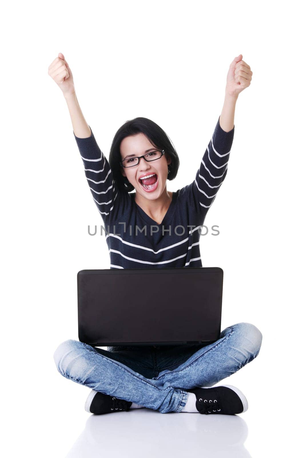 Happy young woman with fists up using her laptop, isolated on white.