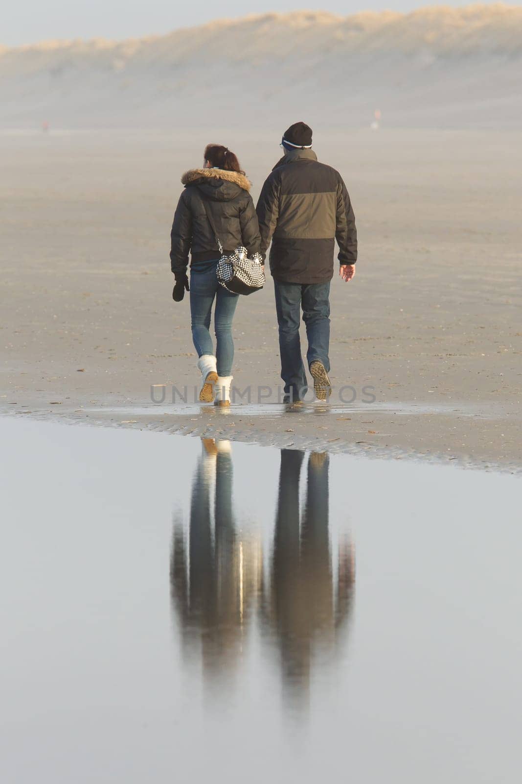 Couple walking on a dutch beach in the winter