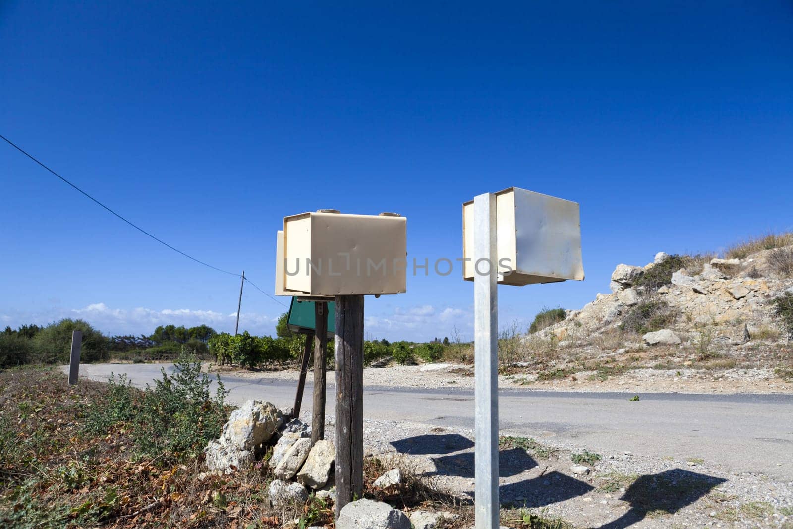 Individual mailboxes on wooden poles stand alone at the roadside
