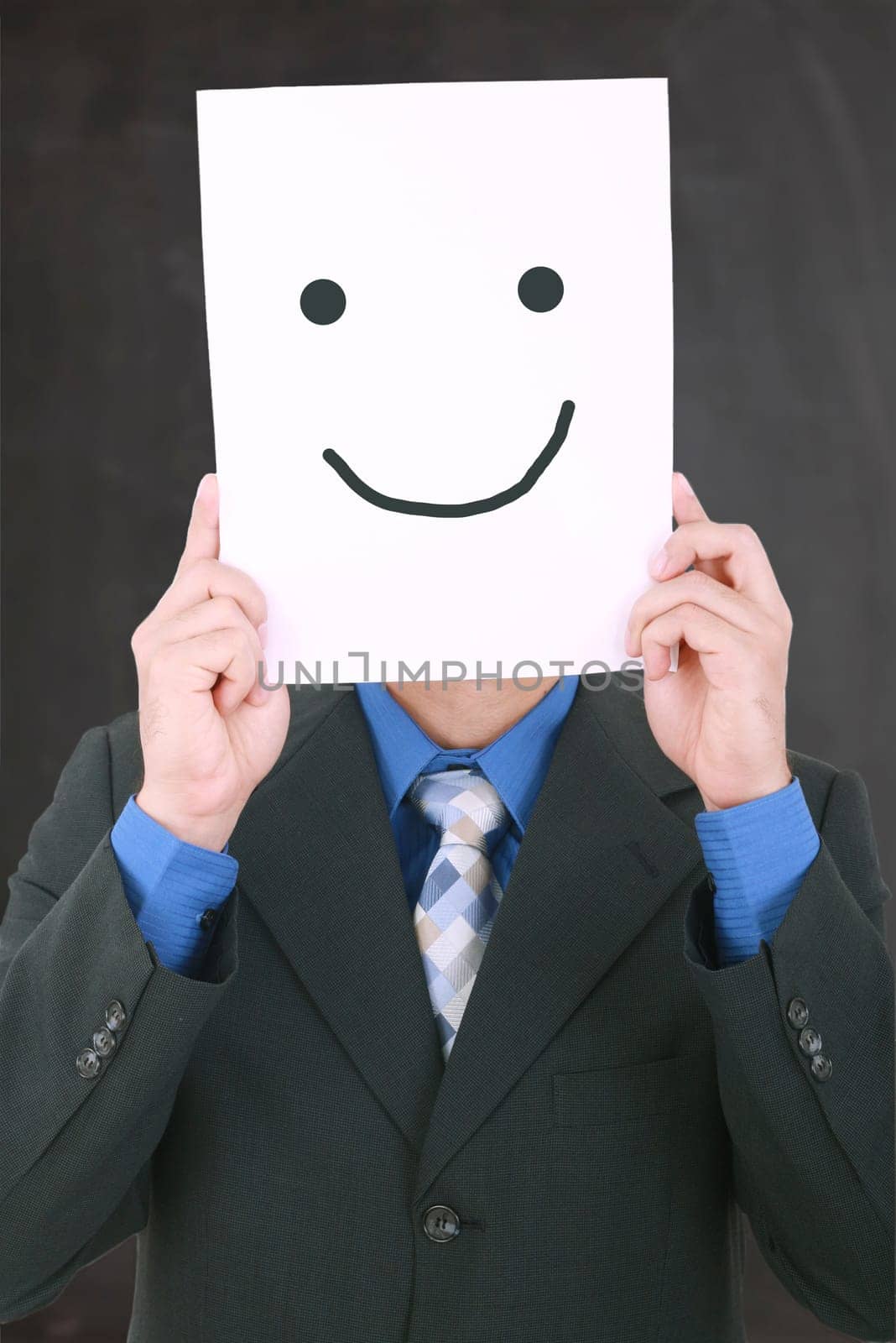 Young businessman hiding his face with a white billboard with a smiley face on it