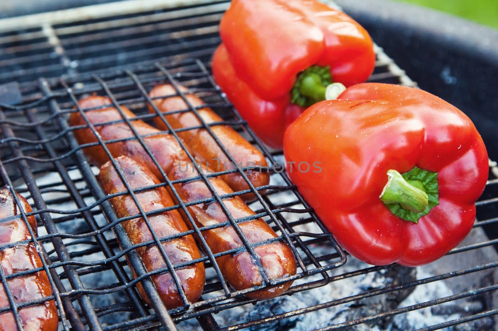 Red sweet pepper and sausages on a grill, close up