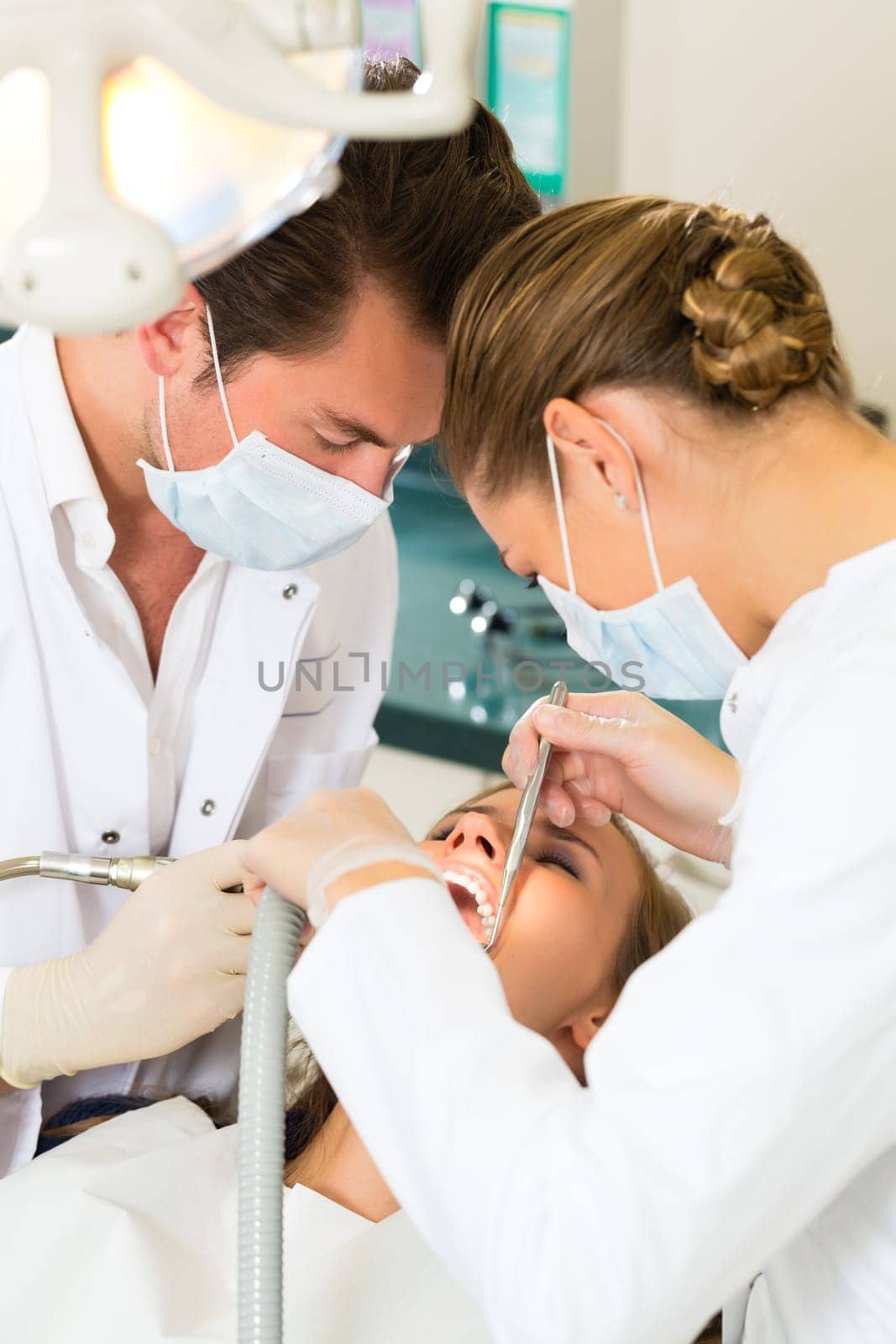 Female patient with dentist and dental assistant during treatment