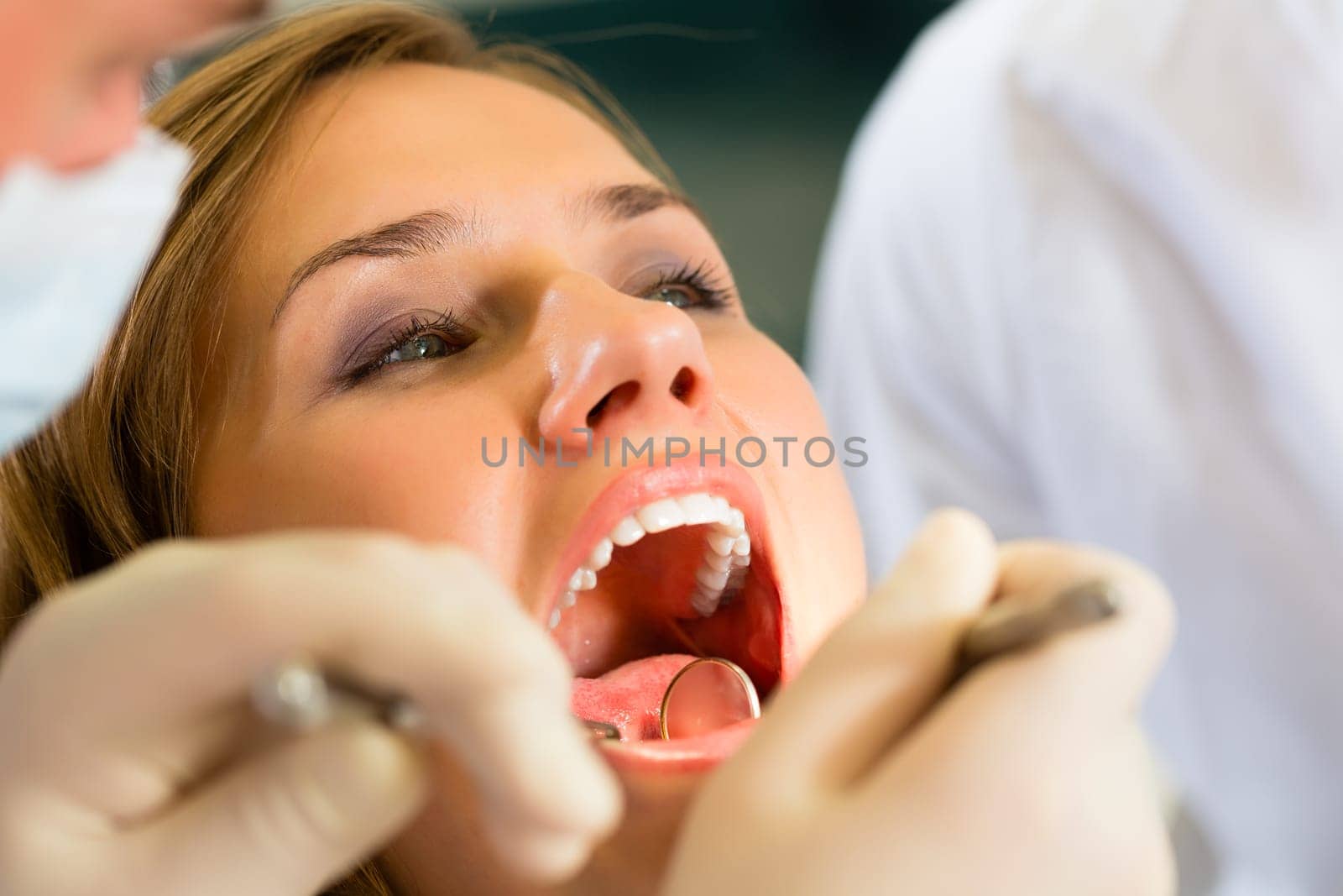 Female patient with dentist and dental assistant during treatment
