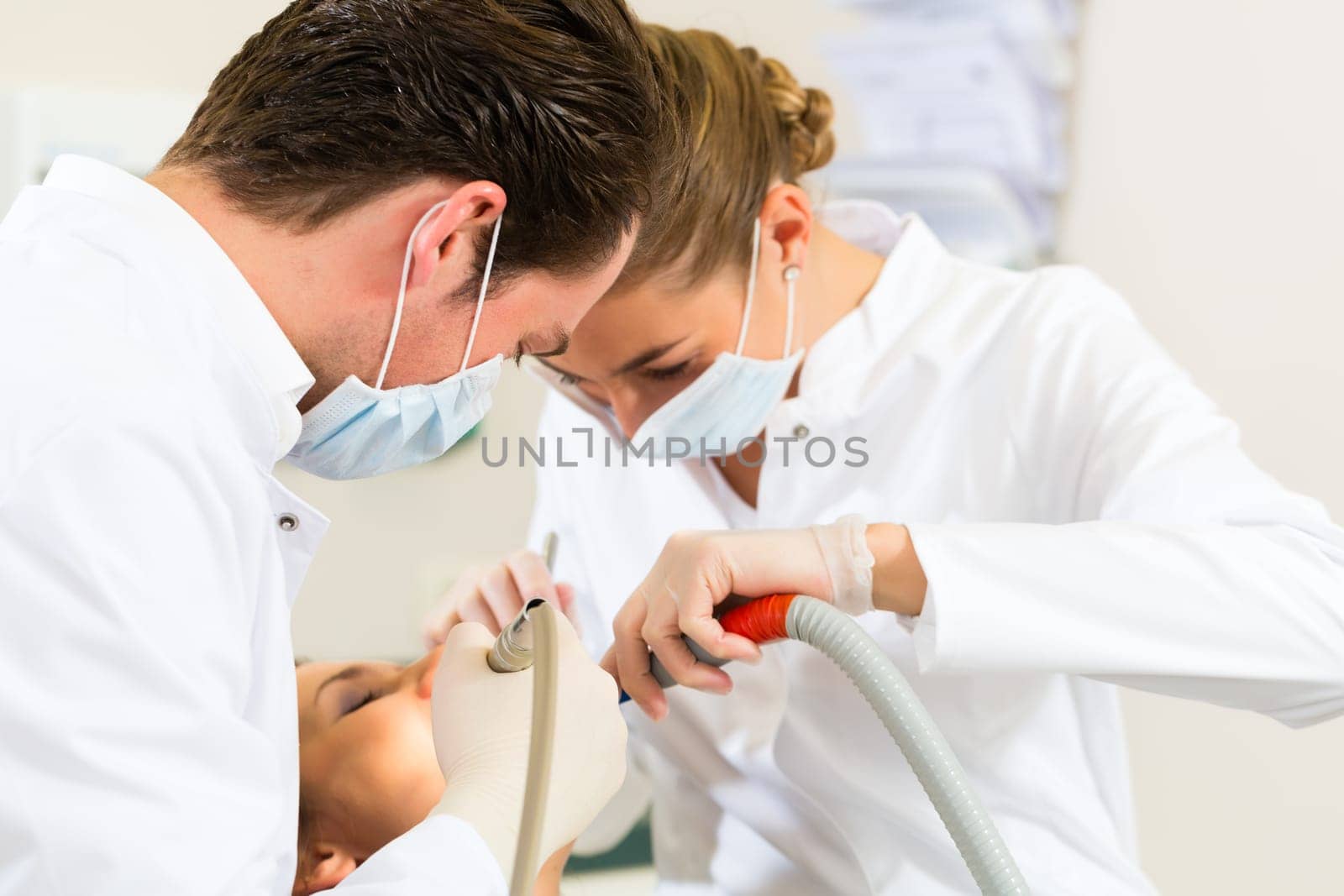 Female patient with dentist and dental assistant during treatment