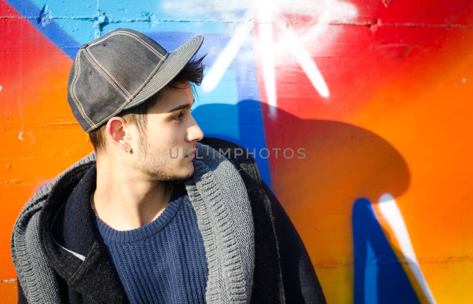 Handsome young man against colorful graffiti covered wall