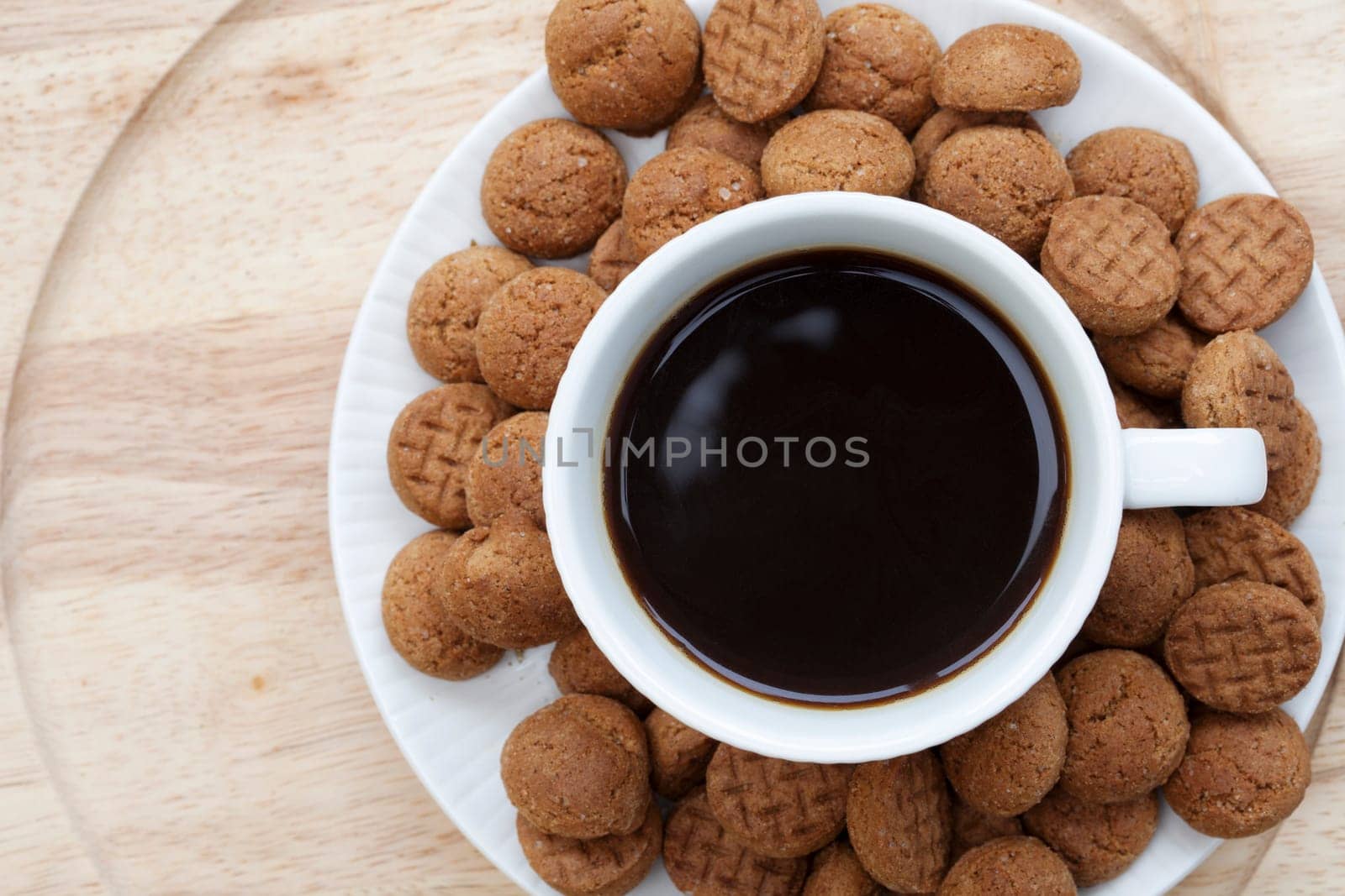 Kruidnootjes surrounding a cup of coffee seen from directly above.