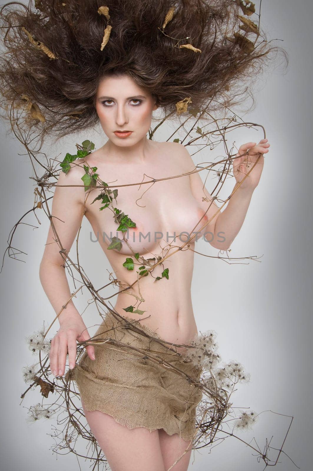 Partial nude of a young woman wrapped in lianas,very high hairstyle and jute dress