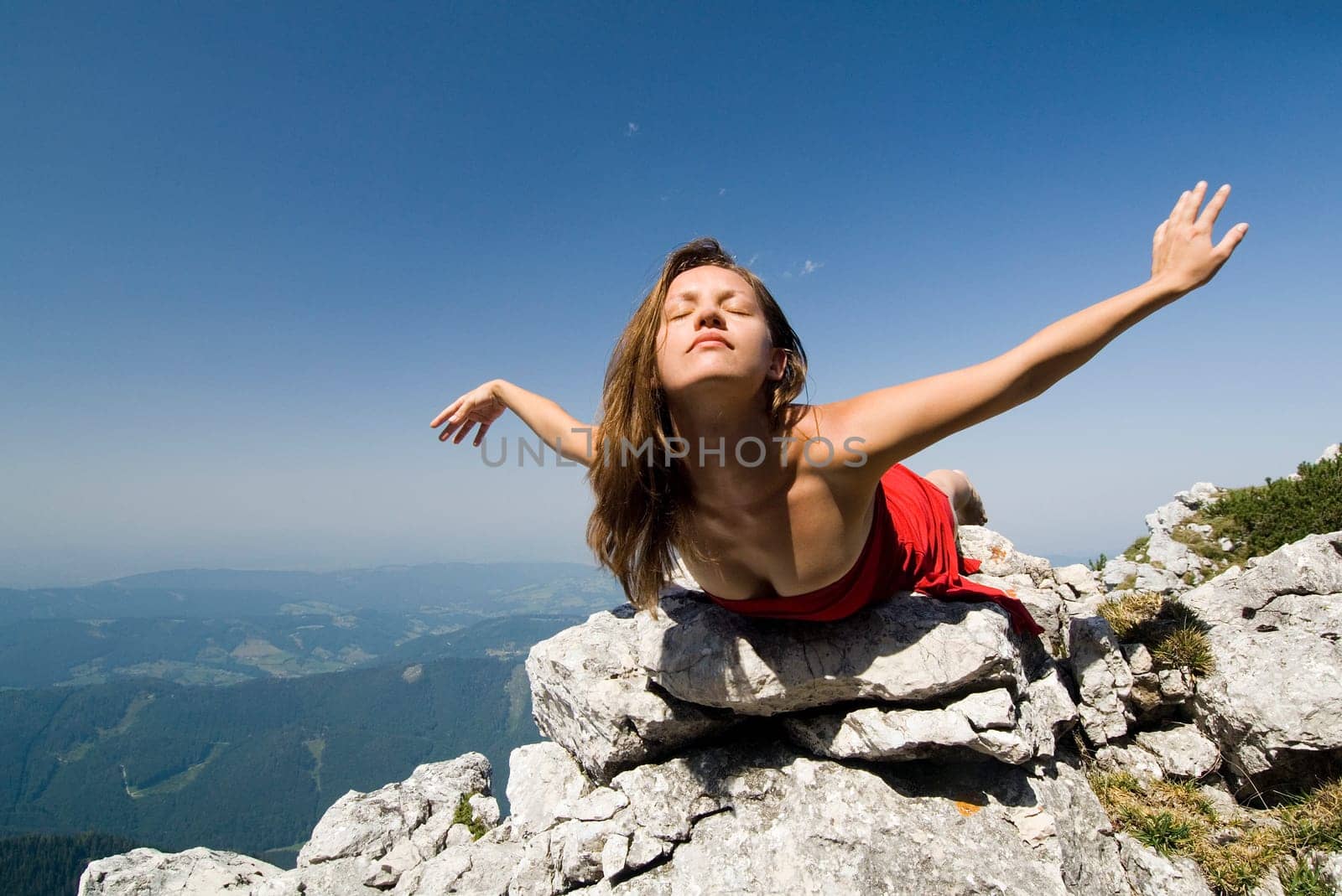 A young woman lies on rocks and floats lightly into the sky