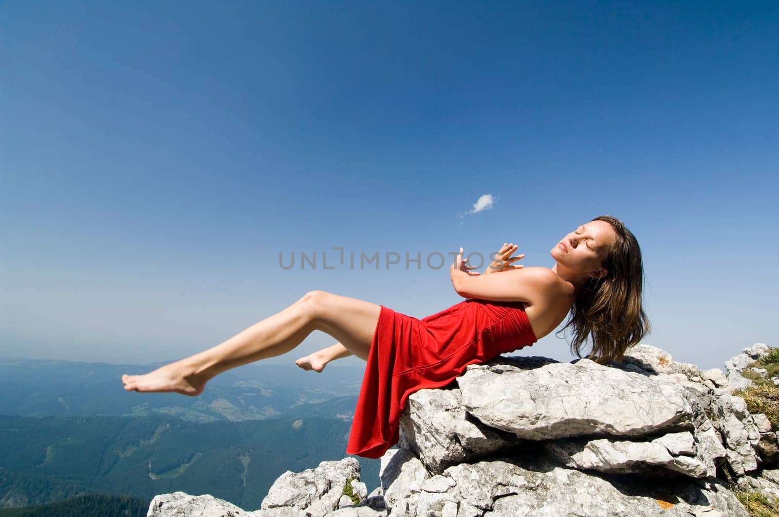 Young slender woman sitting on a rock with her legs outstretched
