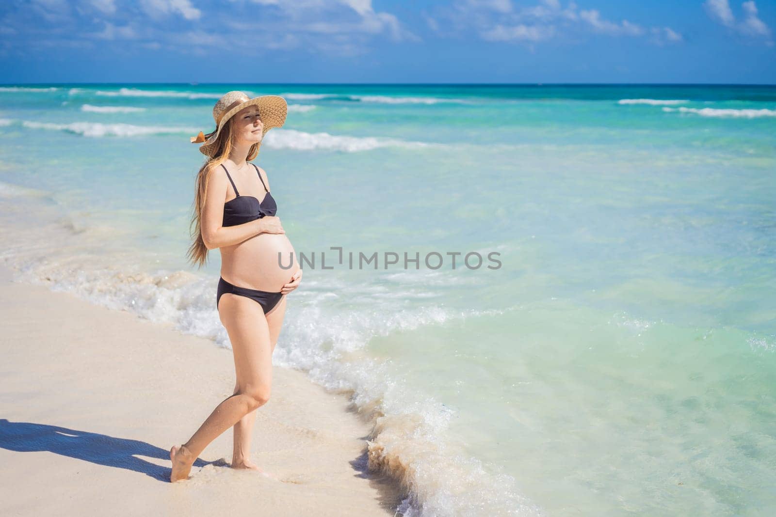 Radiant and expecting, a pregnant woman stands on a pristine snow-white tropical beach, celebrating the miracle of life against a backdrop of natural beauty by galitskaya