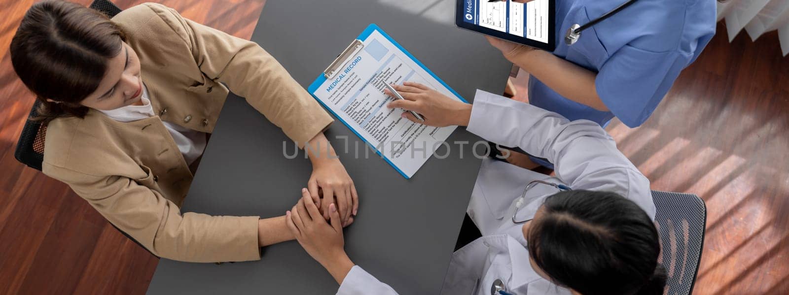 Doctor show medical diagnosis report and providing compassionate healthcare consultation, holding young patient hand for being supportive and professional in doctor clinic office. Top view Neoteric