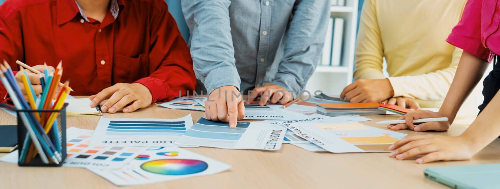 A cropped image of professional interior designer discuss the color material with her colleagues by comparing with color swatches and color palette document. Creative design concept. Variegated.