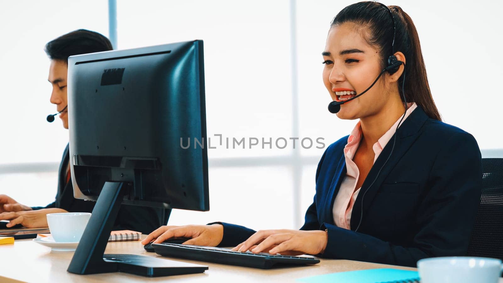Business people wearing headset working in office to support remote customer or colleague. Call center, telemarketing, customer support agent provide service on telephone video conference call. Jivy