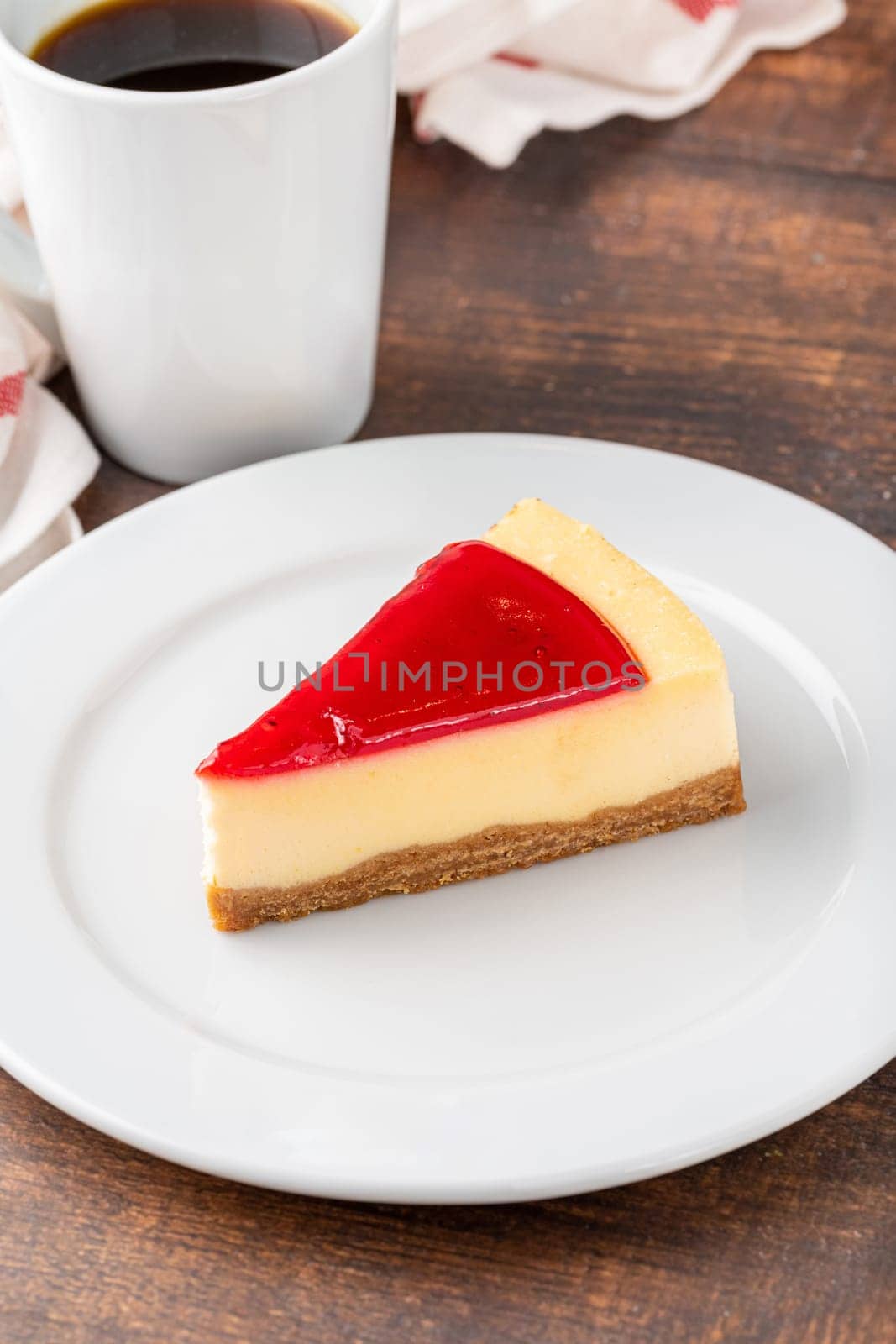 Delicious strawberry cheesecake with coffee next to it on wooden table by Sonat