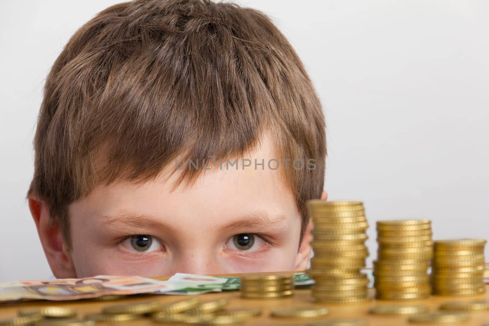 Boy sits in amazement in front of towers of money and bills
