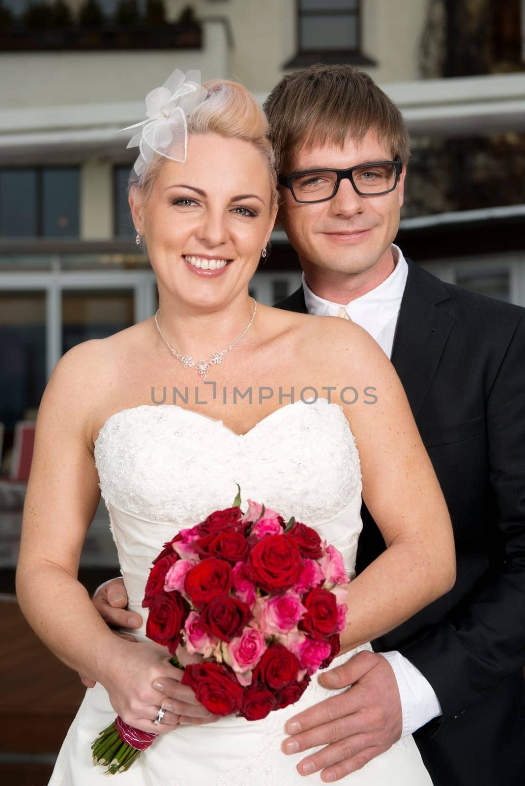 A young bride and groom smile and show the bridal bouquet