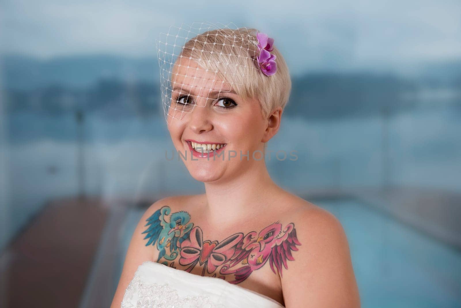 Portrait of a blonde bride with tattoo,in front of Lake Wolfgang