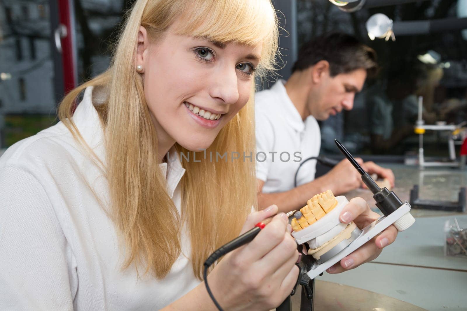 Dental technicial applying wax to a prosthesis model in an articulator
