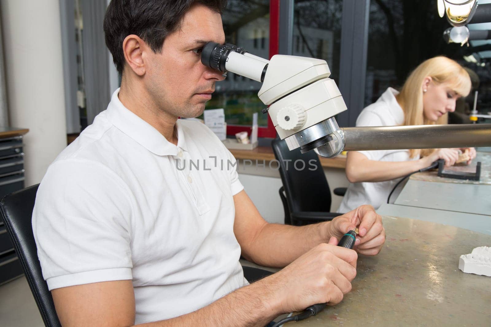 Two dental technicians at their workplace polishing dental prosthesis
