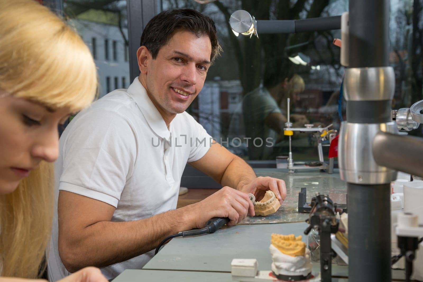Dental technicial with a handpiece in a dental lab polishing the model of a prosthesis.