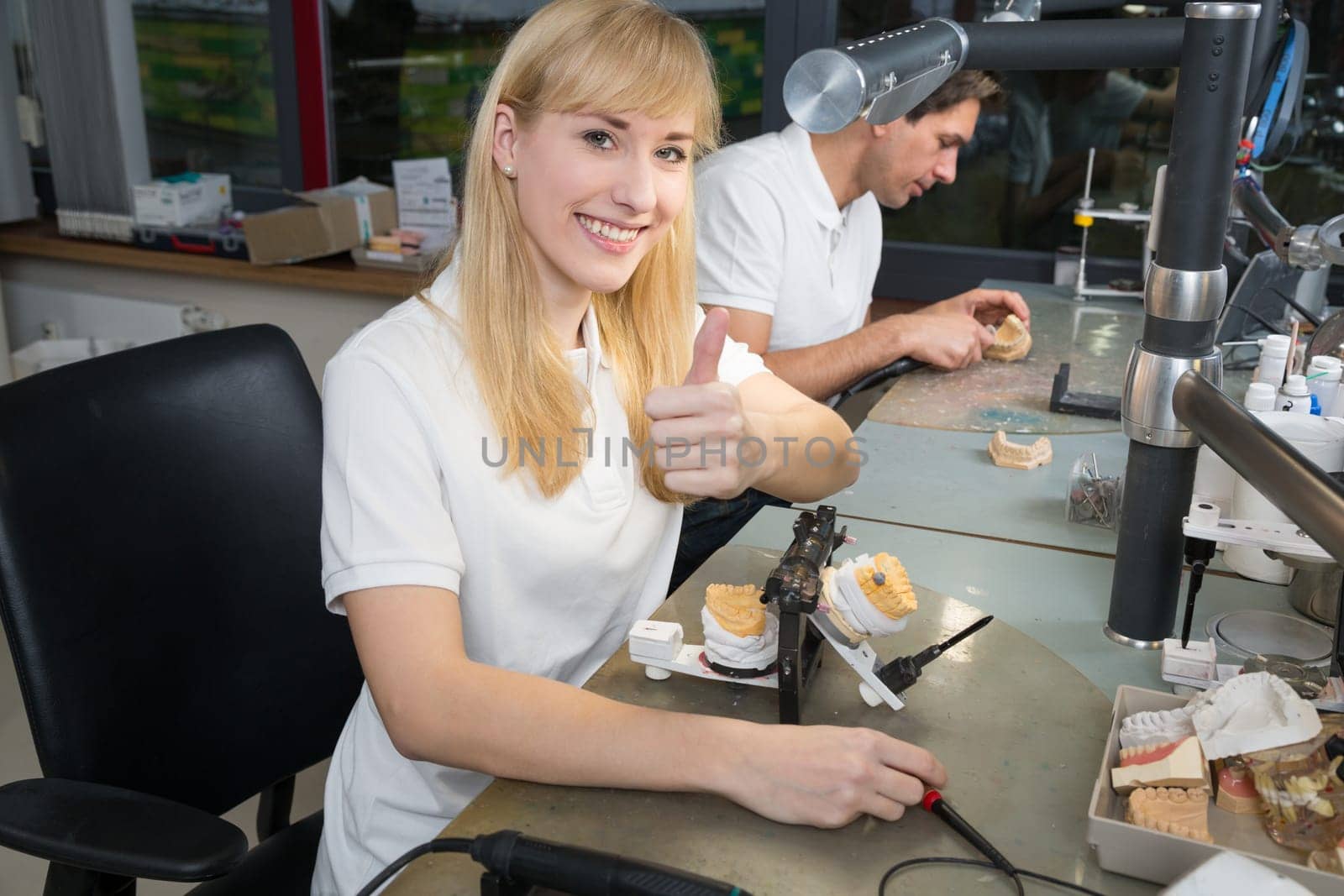 Dental technicial in a dental laboratory with articulator showing thumbs up