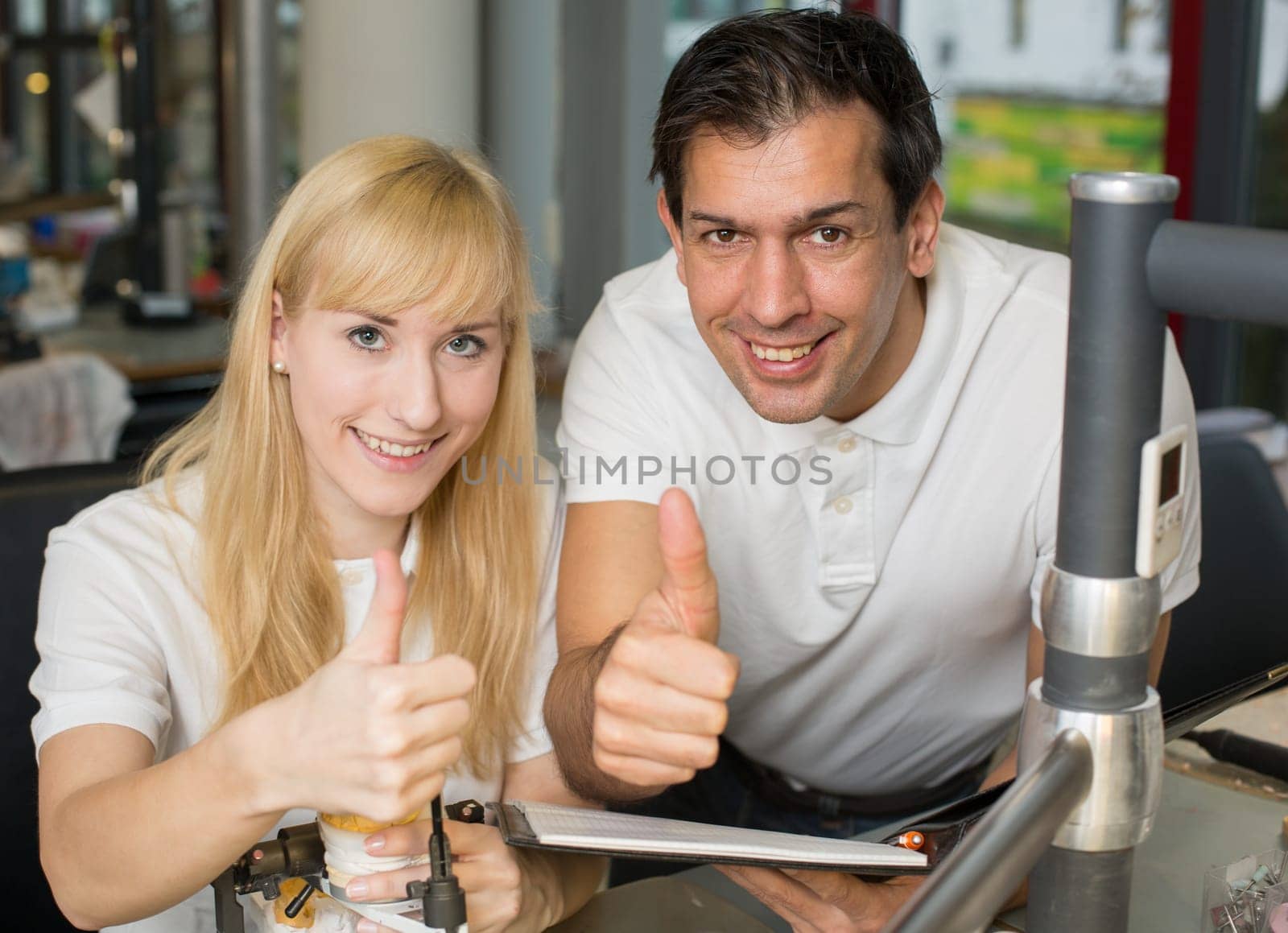 Two dental technicians showing thumbs up in a lab
