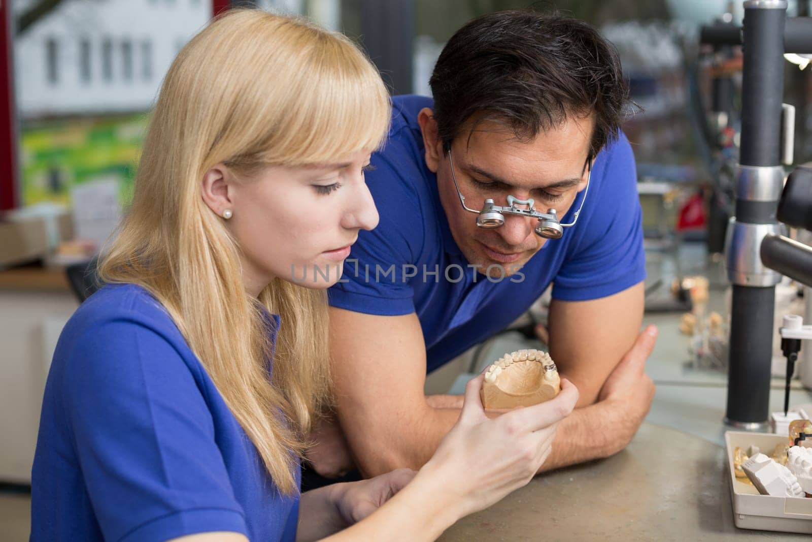 Dental technician or apprentice showing a prosthesis to a collegue or instructor