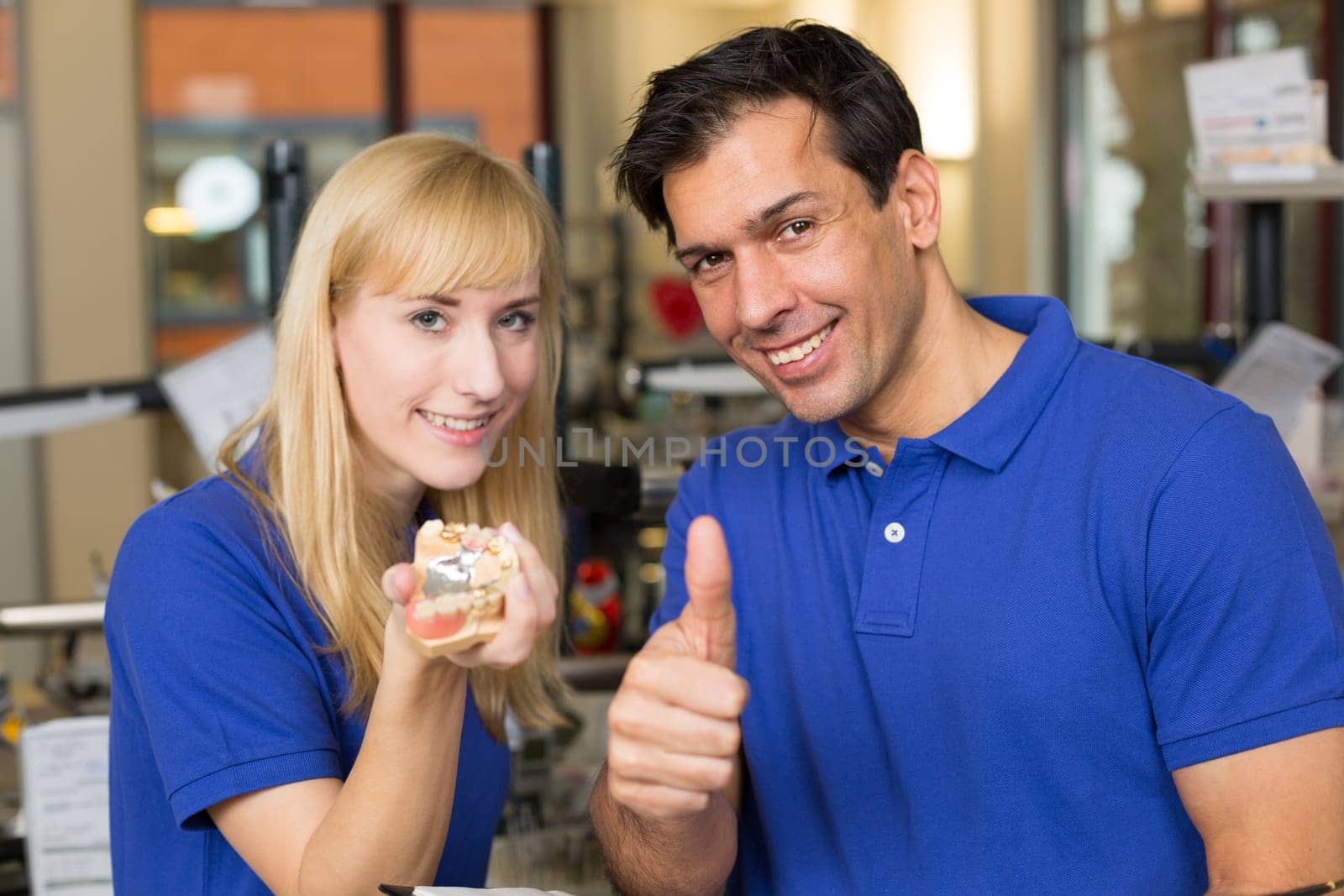 Dental technicians presenting dental prosthesis and showing thumbs up