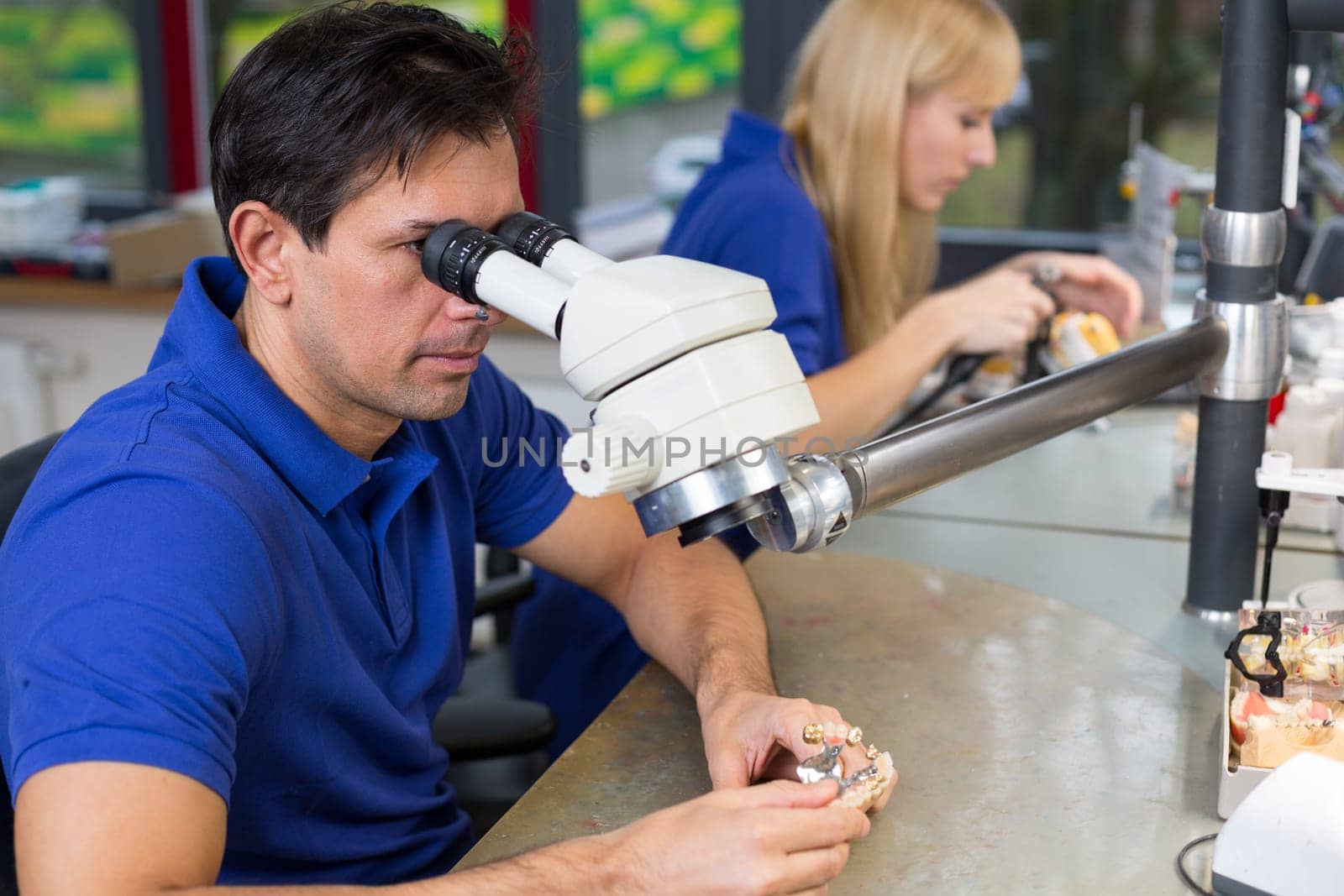 Dental technicians with microscope at work in a lab