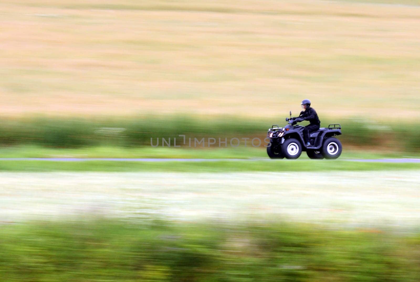 Panning shot of a fast moving black ATV - quad bike