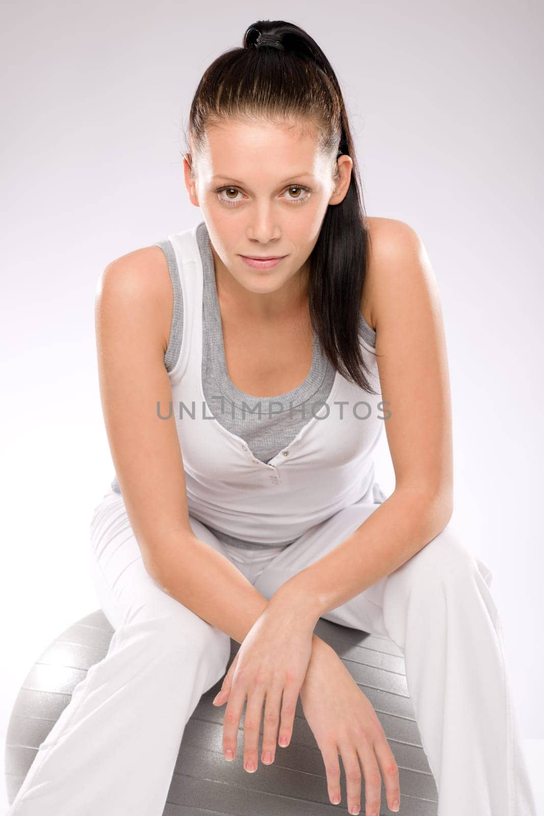 Sporty brunette young woman sitting on fitness ball after exercises