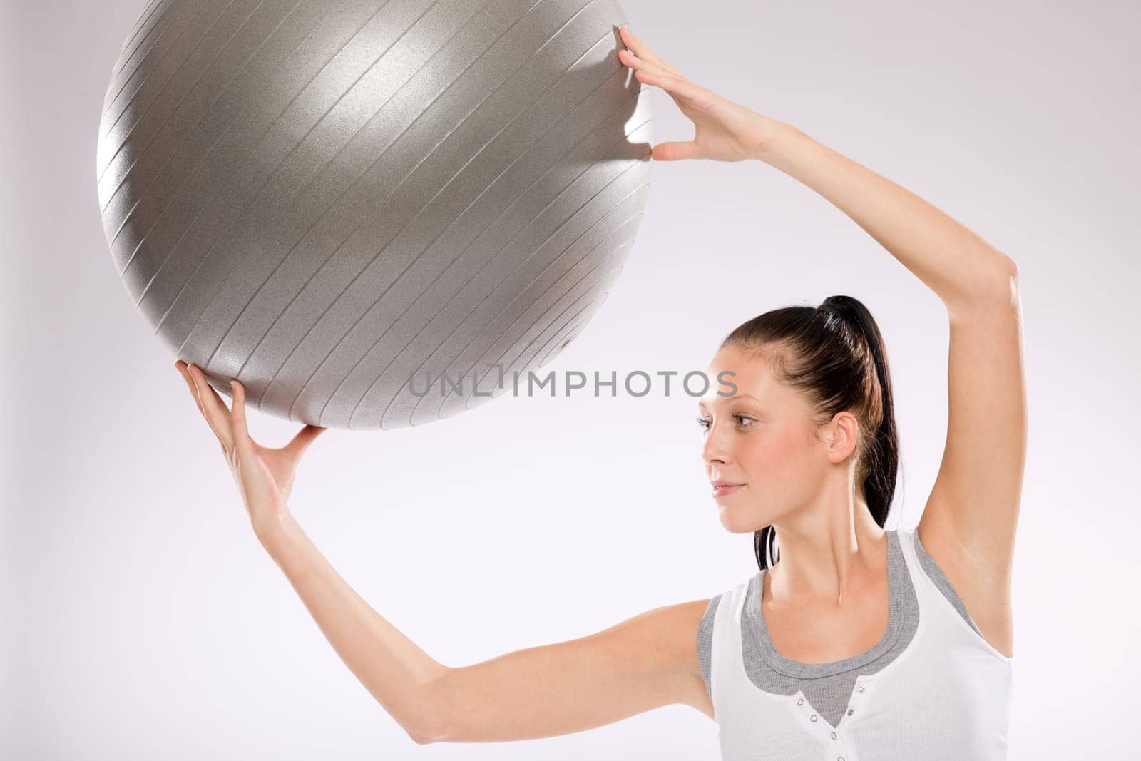 Young woman doing exercises with fitness ball on white background