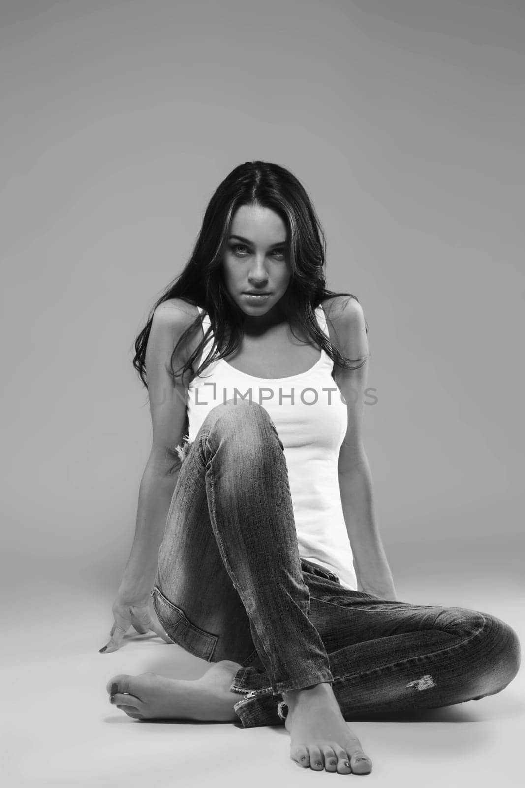 Beautiful woman in jeans sitting on the floor in black and white