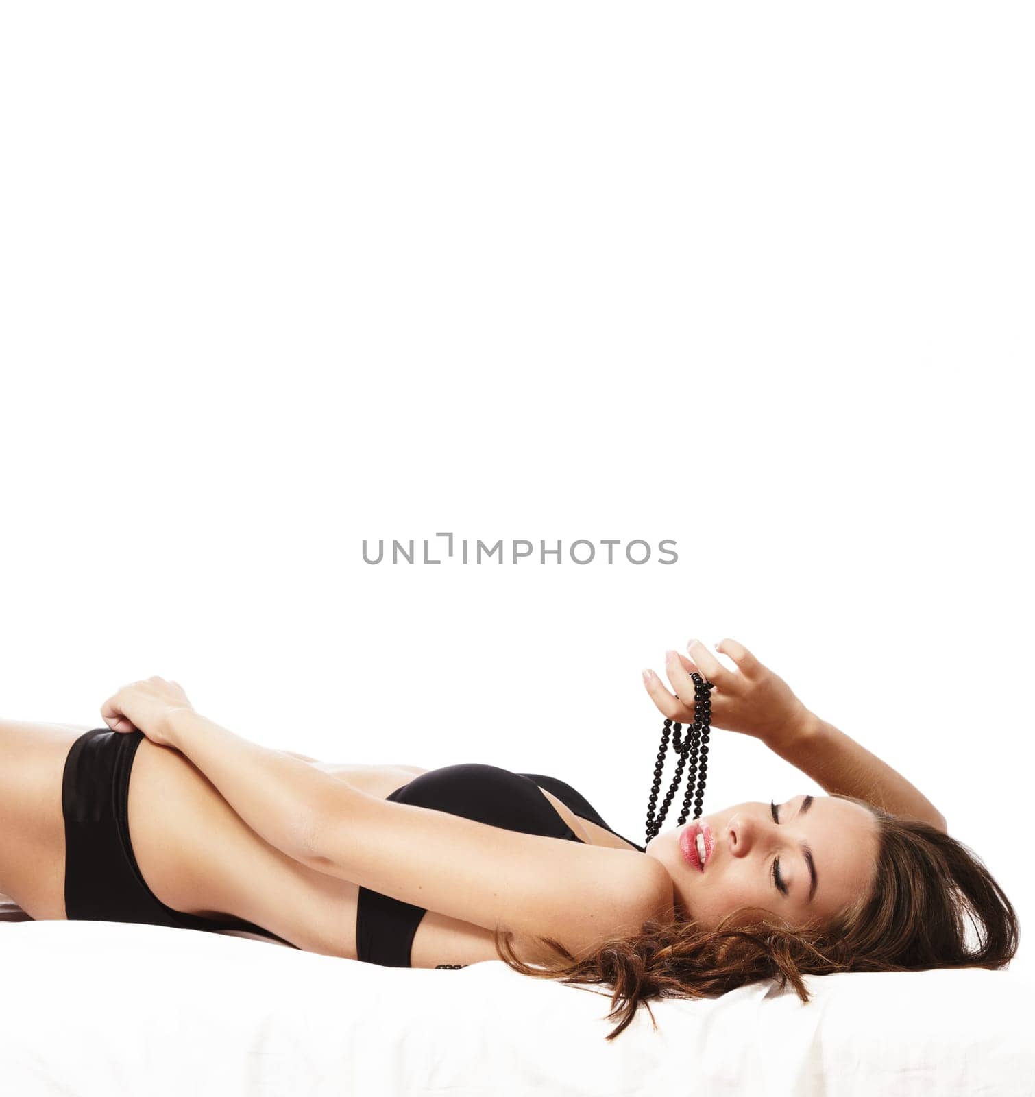Beautiful sensual woman in lingerie lying on bed against white background
