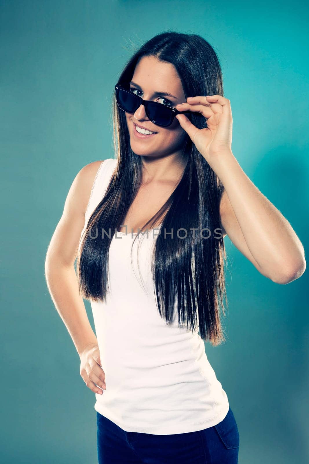 Female teenager in white shirt looking over her sunglasses