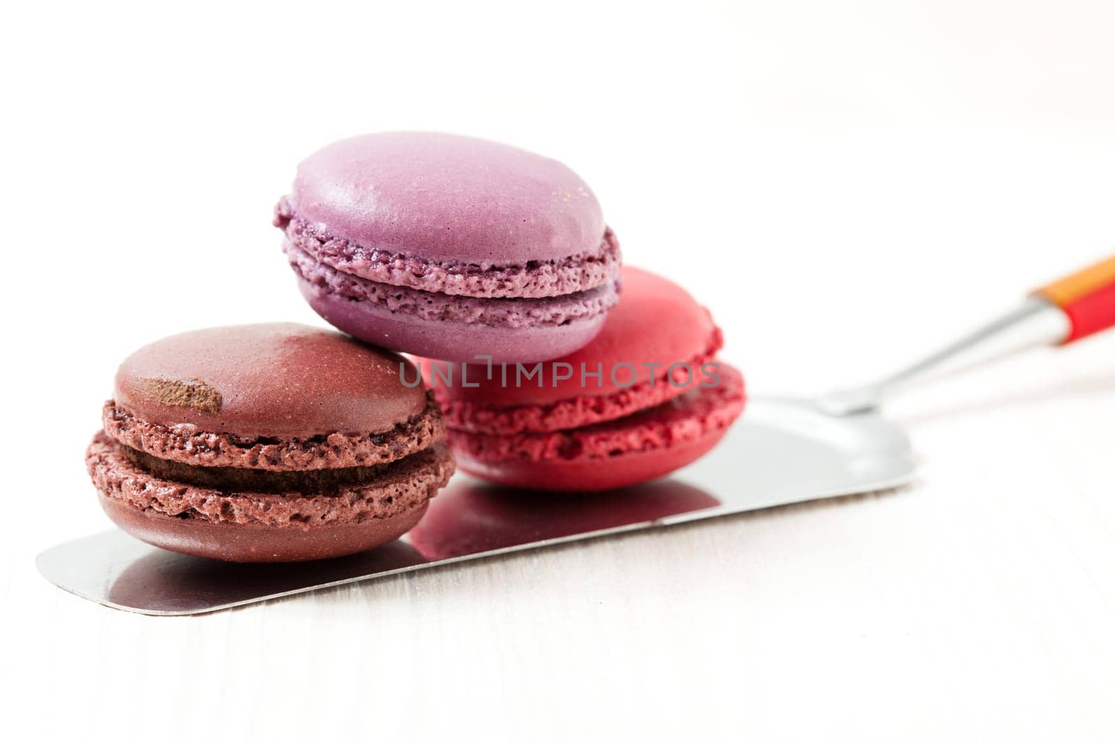 Close-up of three colorful macaroons on cake server on light background