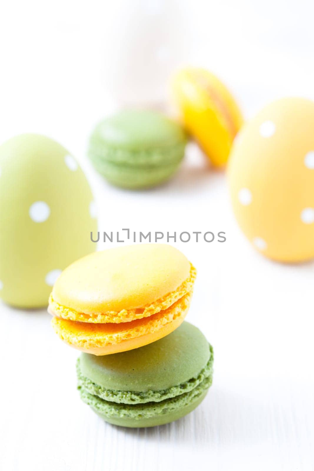 Close-up of colorful macaroons and Easter eggs on light background