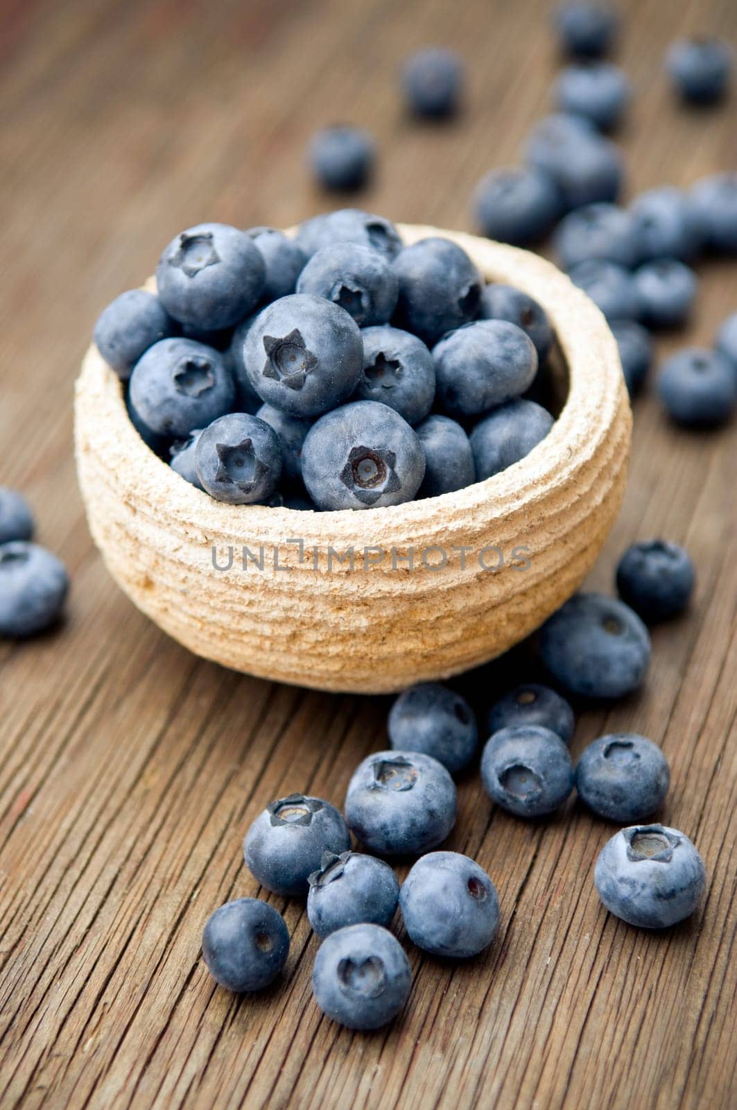 Fresh blueberries in small bowl on wooden surface