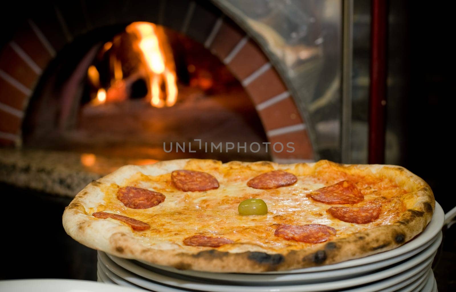Delicious baked pizza in front of oven