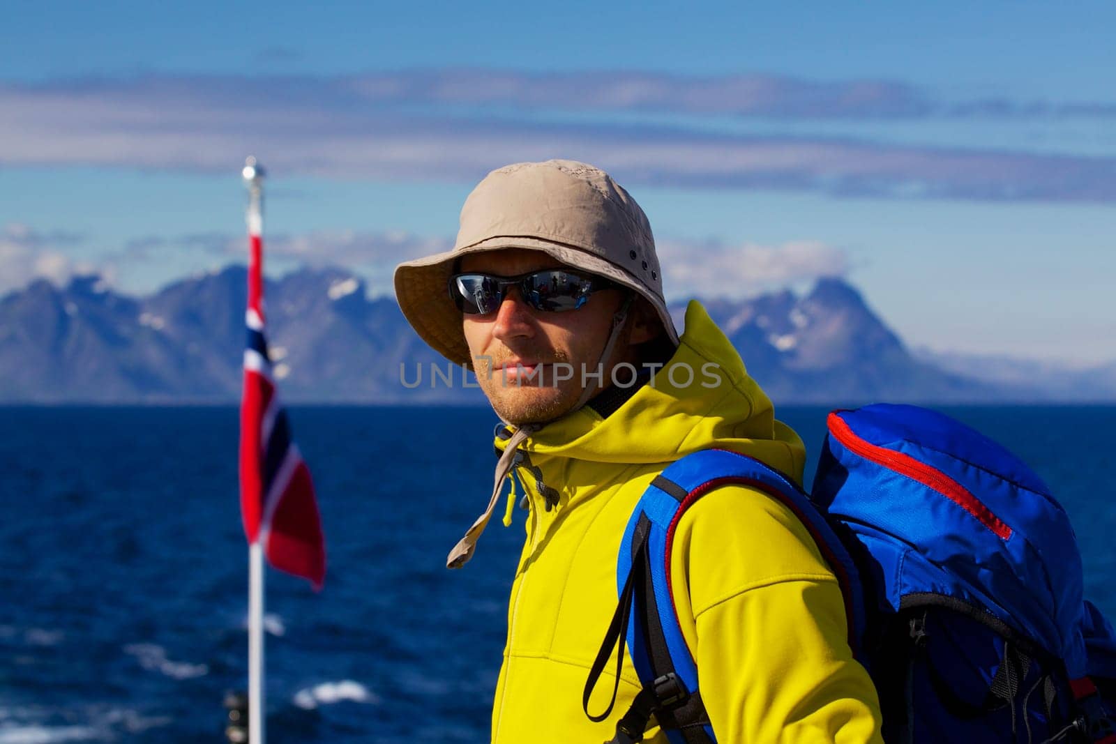 Young man with backpack with panorama of Lofoten islands in Norway in the background