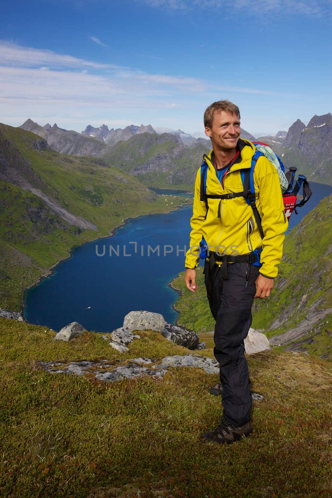 Young active man with backpack hiking on Lofoten islands in Norway on sunny day