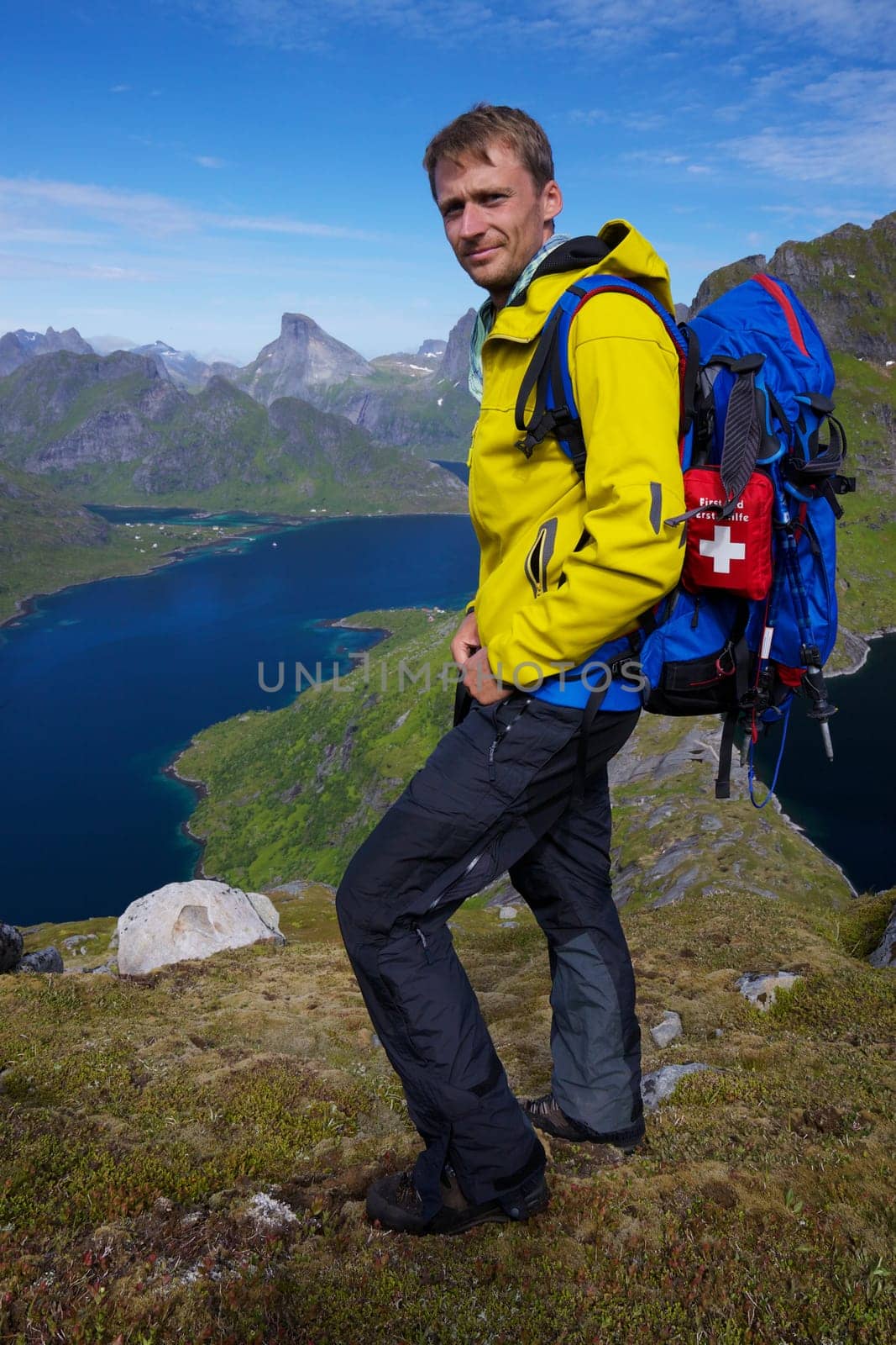 Young active man with backpack hiking on beautiful Lofoten islands in Norway on sunny day