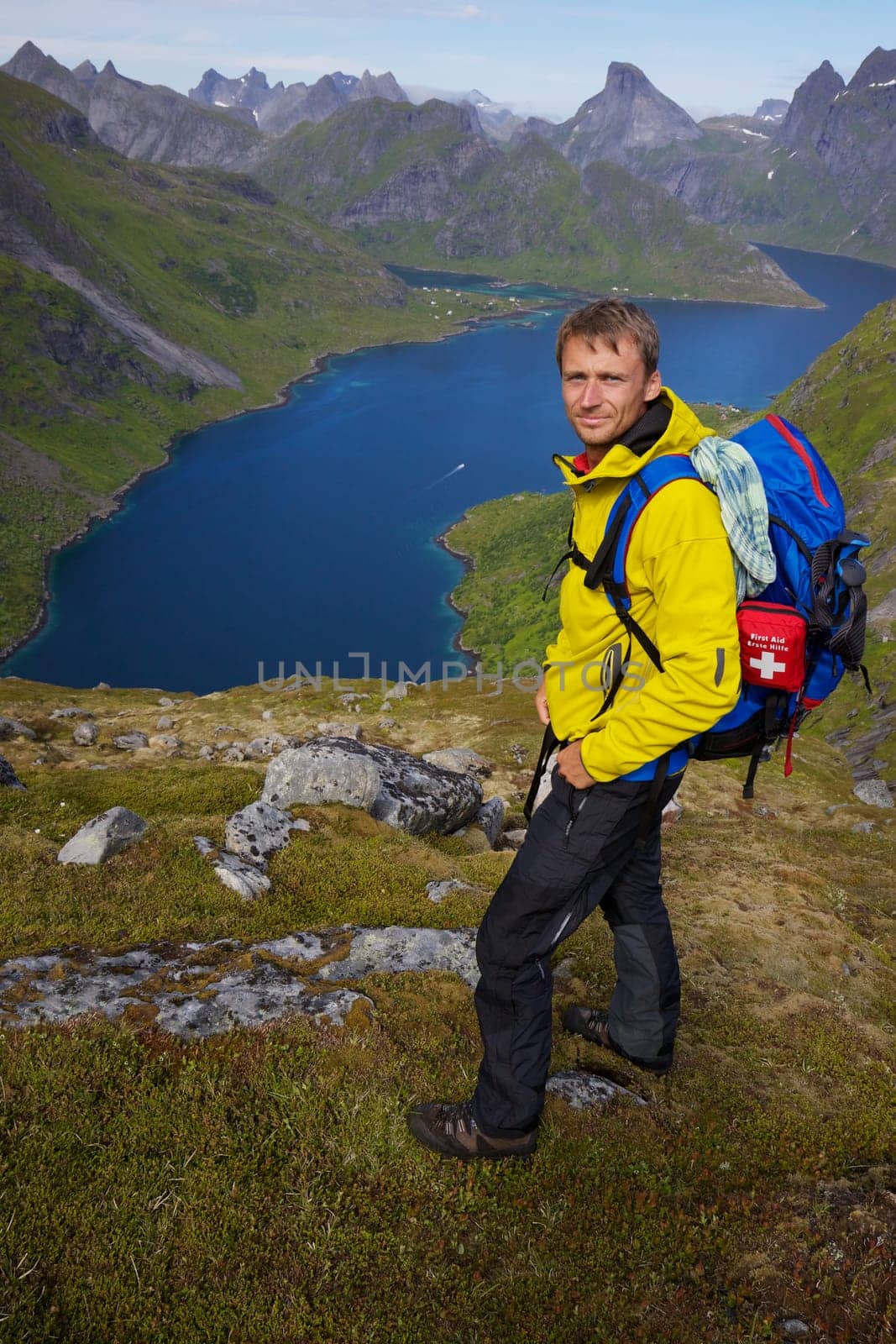 Young active man with backpack hiking on Lofoten islands in Norway on sunny day