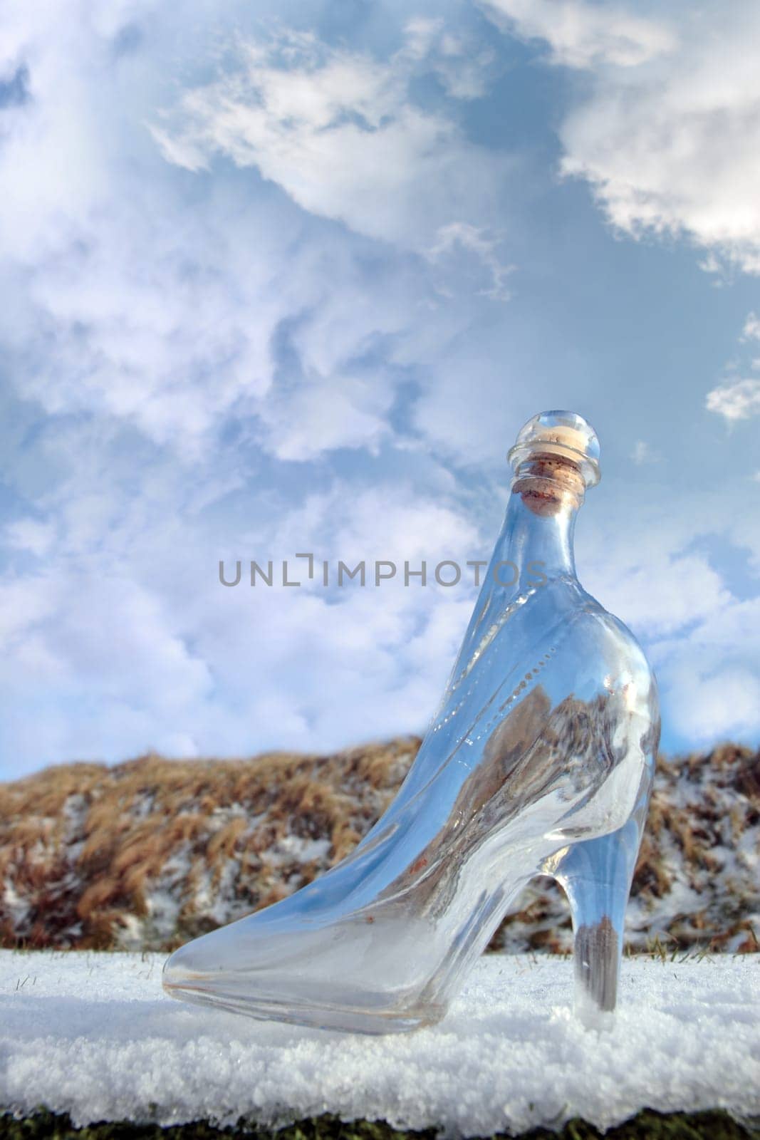 a glass slipper on a snow covered surface with a cloudy sky background