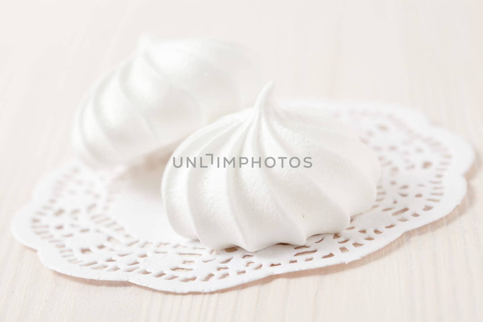 White meringues resting on white decorative mat on light background