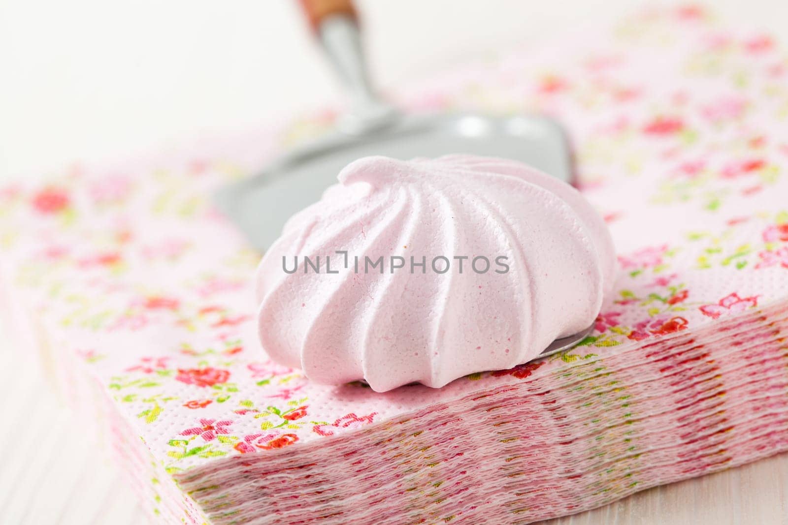 Pink meringue resting on server and serviettes