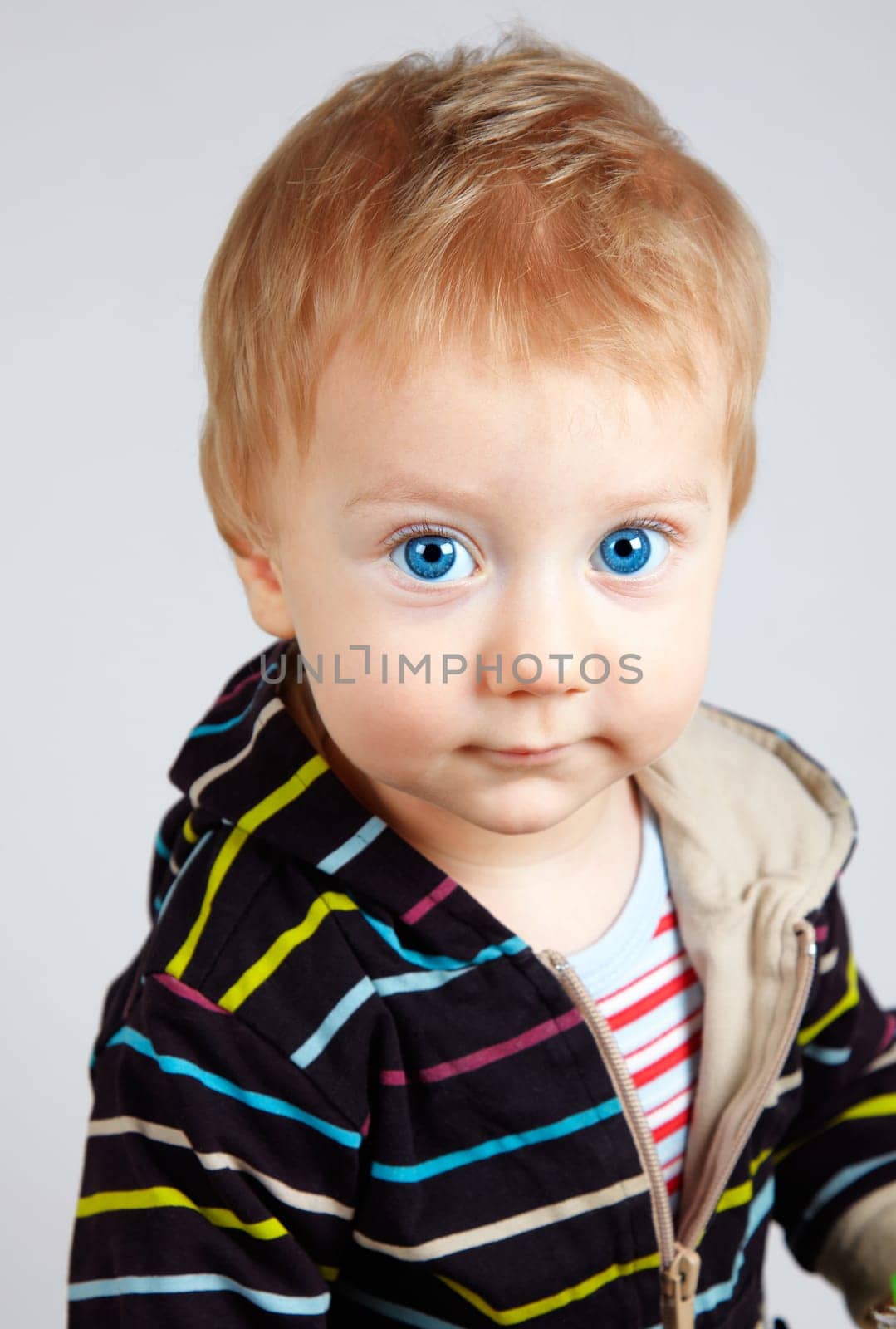 Studio portrait of a happy one year old baby boy on grey background.