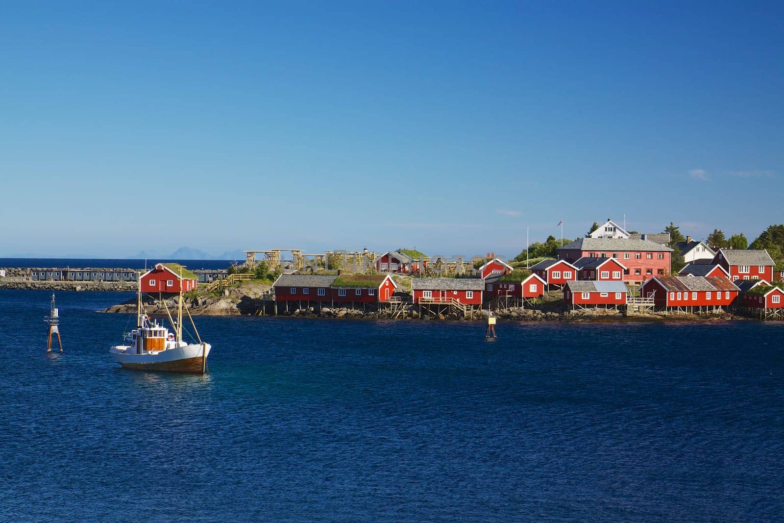 Red fishing rorbu huts and fishing boat in town of Reine on Lofoten islands